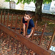 Louis a rejoint le concours — aidez-le/la à gagner de superbes lots ! autumn, boy, building, casual_clothing, child, daylight, door, grass, leaves, nature, outdoor, park, playful, shorts, smiling, stone_wall, tree, tshirt, window, wooden_fence