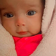 Sephora is registered to the contest to win money with this photo: baby, blanket, cheeks, child, close_up, cozy, cute, eyes, face, head, hooded_blanket, indoors, infant, looking_at_camera, photograph, pink_clothing, portrait, red_clothing, soft_texture, wide_eyed