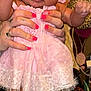 baby, child, pink_dress, socks, hands, adult, nail_polish, face, fingers, couch, leopard_print, home_interior, curious_expression, skin, person, furniture, portrait, indoor, holding, cute
