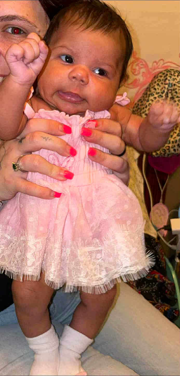 Mckenna joined the competition — help win amazing prizes! baby, child, pink_dress, socks, hands, adult, nail_polish, face, fingers, couch, leopard_print, home_interior, curious_expression, skin, person, furniture, portrait, indoor, holding, cute