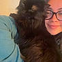 Benson is registered to the contest to win money with this photo: person, cat, glasses, indoor, cozy, hugging, black_cat, long_hair, smile, casual_clothing, portrait, furry, comfort, face, pet, animal, friendship, soft_light, warm_tone, close_up