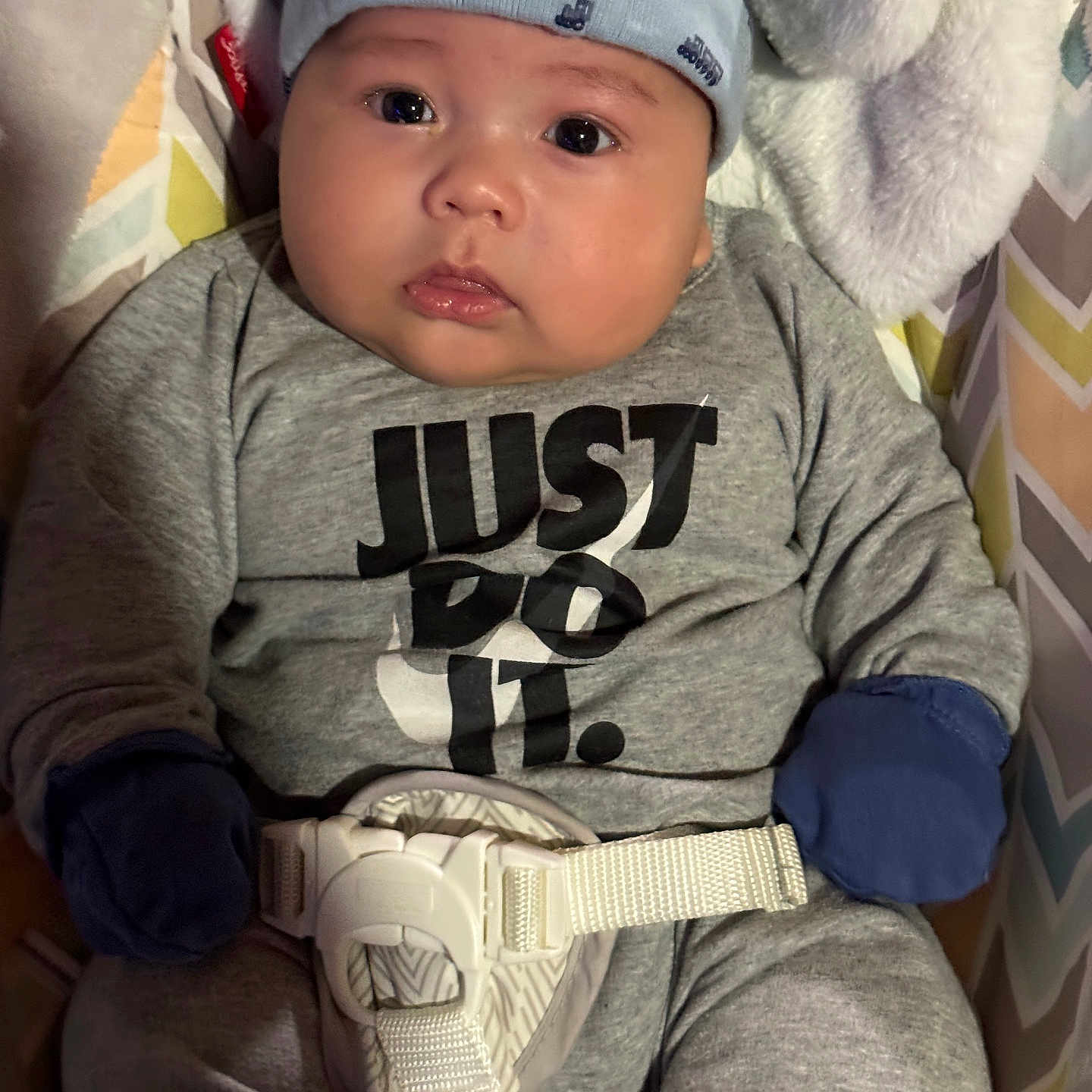 Aziel is registered to the contest to win money with this photo: baby, infant, hat, mittens, grey_outfit, sitting, baby_seat, patterned_background, face, eyes, expression, clothing, belt, closeup, indoor, child, cute, portrait, newborn, warm