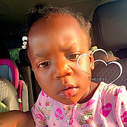Marsai is registered to the contest to win money with this photo: bear_pattern, car_interior, car_seat, casual, child, cute, daylight, expression, face, hair_beads, heart_pattern, indoors, patterned_clothing, person, pink_clothing, portrait, seat, sunlight, toddler, window