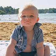 Ezra joined the competition — help win amazing prizes! baby, child, beach, sand, water, towel, shirt, sunlight, outdoor, summer, portrait, blue_shirt, swimwear, sitting, face, cute, young_child, nature, daytime, vacation