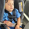 toddler, child, sleeping, car_seat, seatbelt, blue_shirt, shorts, bracelet, indoor, car_interior, safety, resting, cute, baby, young_child, peaceful, hands, face, hair, clothing