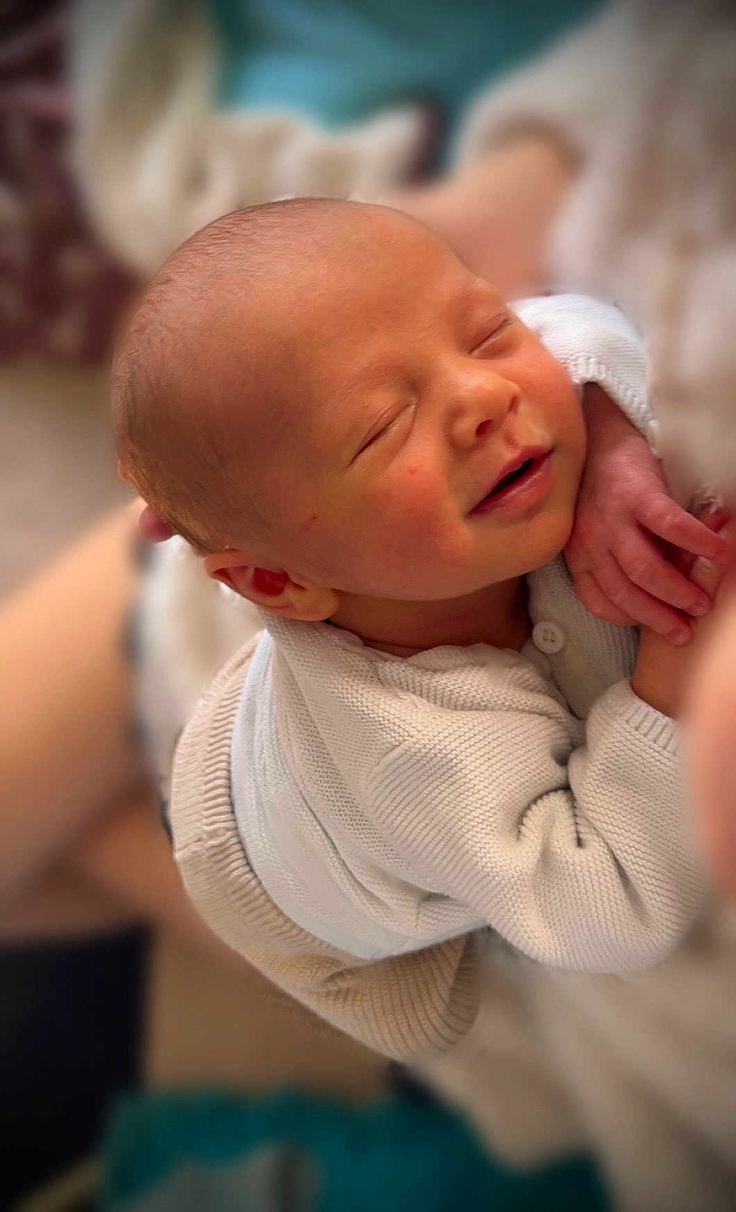 Hélyas a rejoint le concours — aidez-le/la à gagner de superbes lots ! baby, newborn, infant, sleeping, smiling, face, head, hand, white_sweater, knitwear, cozy, portrait, closeup, bed, blanket, parent_arm, skin, peaceful, soft_focus, shallow_depth_of_field