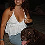 Mango a rejoint le concours — aidez-le/la à gagner de superbes lots ! woman, dog, chocolate_labrador, smiling, sitting, outdoor, night, casual, panting, jeans, white_top, bracelet, curly_hair, happy, pet, animal, friendship, human, person, dark_background