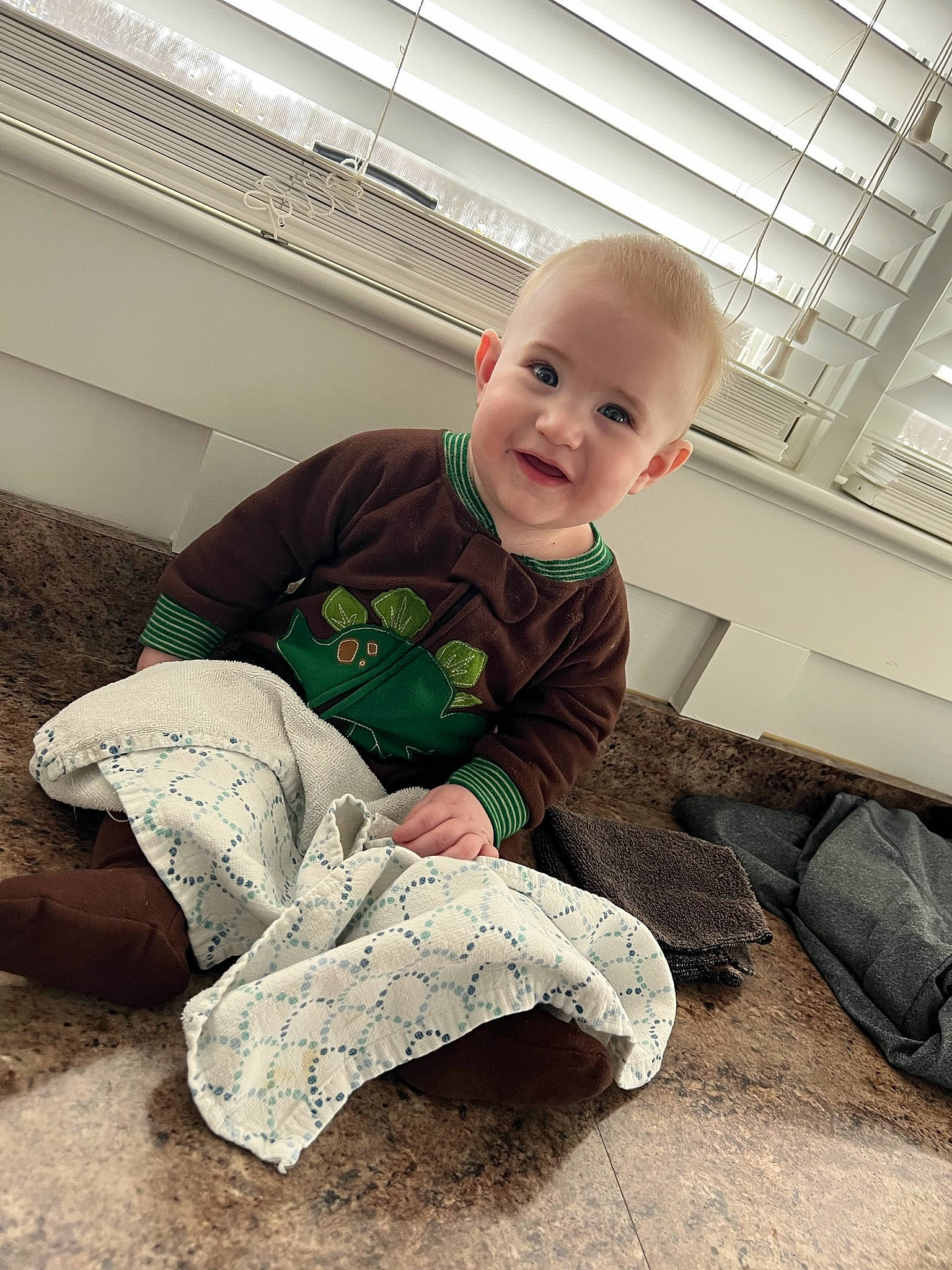Reid is registered to the contest to win money with this photo: baby, baby_toddler_clothing, child, comfort, floor, flooring, foot, fun, grass, hairstyle, knee, leg, person, shoe, sitting, sleeve, smile, sneakers, standing, t_shirt