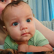 Baruk is registered to the contest to win money with this photo: adult, baby, blanket, blue_eyes, child, close_up, cozy, curtains, cute, eyes, face, green_clothing, indoors, infant, parent, photography, portrait, round_cheeks, sitting, soft_lighting