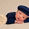 Anthony joined the competition — help win amazing prizes! baby, newborn, infant, child, portrait, sleeping, awake, blue_outfit, knitted_clothing, cap, hat, folded_hands, wooden_sign, milestone, one_week_old, studio_photography, beige_background, closeup, cute, safe