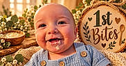 Anthony joined the competition — help win amazing prizes! baby, bib, blue_clothing, buttons, child, face, first_bites, flowers, food, happy, indoor, infant, messy_face, overalls, plants, portrait, rustic, smiling, warm_lighting, wooden_sign