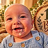 Anthony joined the competition — help win amazing prizes! baby, child, infant, smiling, happy, portrait, face, first_bites, food, messy_face, bib, blue_clothing, overalls, buttons, indoor, rustic, wooden_sign, flowers, plants, warm_lighting