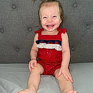 Paisley is registered to the contest to win money with this photo: toddler, child, smiling, happy, sitting, pigtails, red_outfit, clothing, barefoot, feet, face, person, indoor, couch, gray_couch, fabric, cute, young_child, portrait, playful