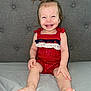 toddler, child, smiling, happy, sitting, pigtails, red_outfit, clothing, barefoot, feet, face, person, indoor, couch, gray_couch, fabric, cute, young_child, portrait, playful