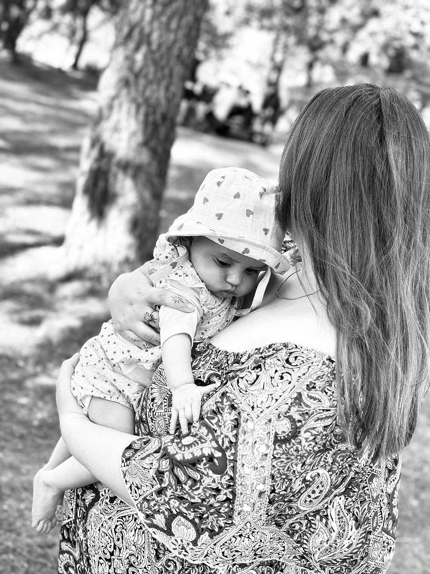 Ivanna a rejoint le concours — aidez-le/la à gagner de superbes lots ! baby, woman, holding, outdoor, tree, hat, patterned_dress, black_and_white, infant, nature, portrait, child, curious, sunhat, person, grass, daylight, hand, back_view, love