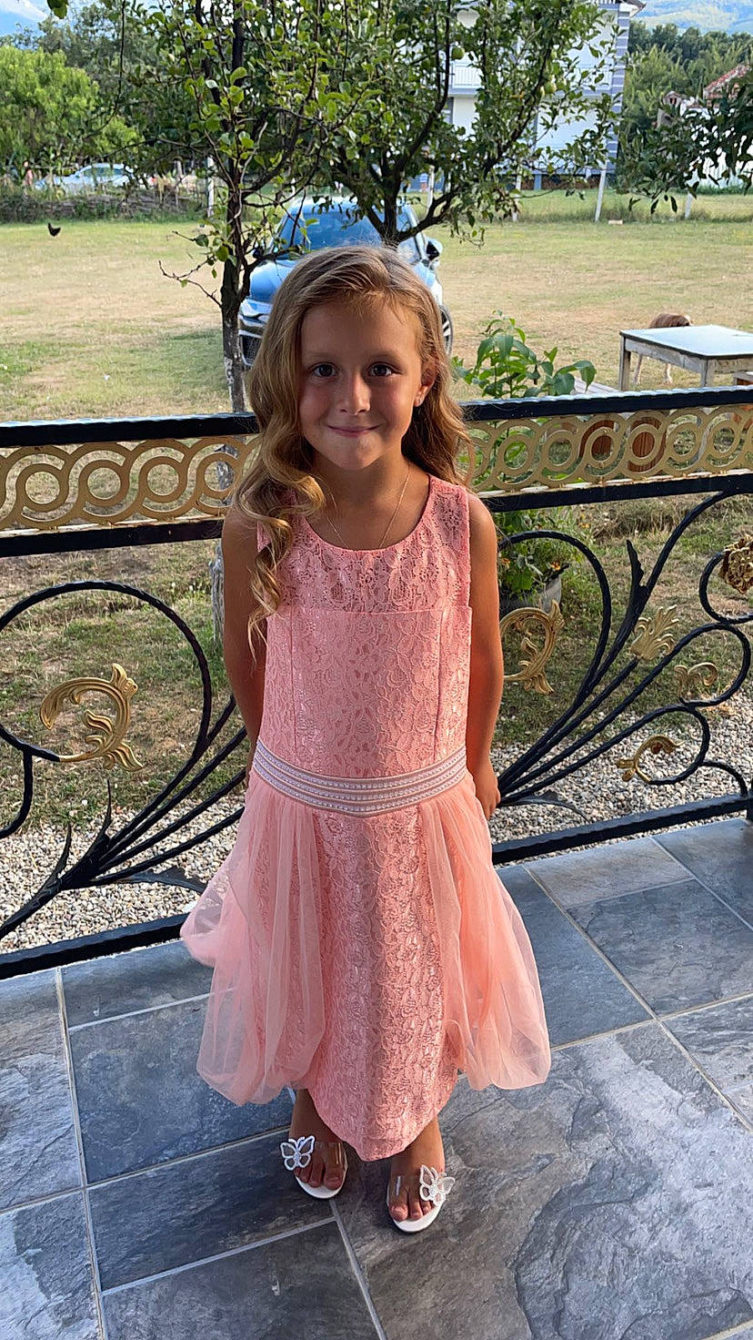 Valentina participe au concours pour gagner de l'argent avec cette photo : botany, day_dress, dress, event, eye, footwear, formal_wear, grass, hairstyle, happy, head, joy, leisure, one_piece_garment, person, pink, plant, skin, smile, toddler