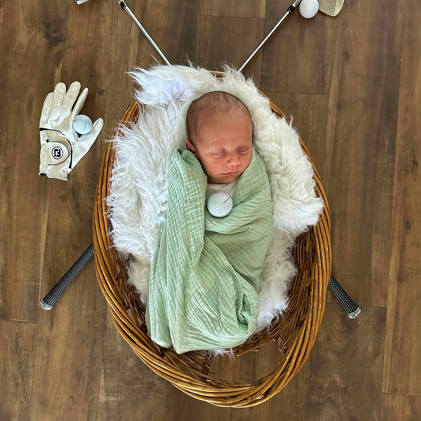 Noah joined the competition — help win amazing prizes! baby, basket, blanket, child, cozy, cute, floor, fluffy, golf_ball, golf_clubs, golf_glove, indoor, newborn, portrait, resting, sleeping, sports_theme, swaddled, wicker, wood_floor
