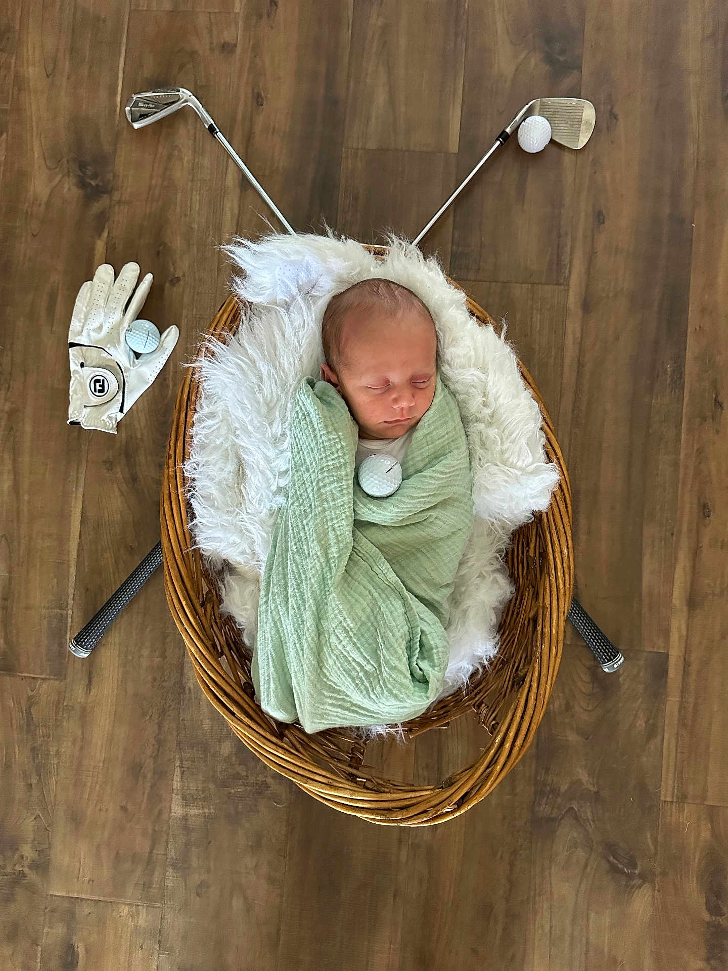 Noah joined the competition — help win amazing prizes! newborn, baby, sleeping, blanket, basket, wicker, fluffy, floor, wood_floor, golf_clubs, golf_ball, golf_glove, indoor, cozy, swaddled, cute, resting, child, sports_theme, portrait
