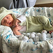 Noah joined the competition — help win amazing prizes! baby, sleeping, green_clothing, hat, basket, blanket, golf_balls, indoor, cozy, infant, soft_texture, cute, resting, child, person, closeup, home, floor, relaxing, peaceful