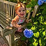 toddler, child, bench, wood, flower, hydrangea, blue_flower, green_leaves, outdoor, sunlight, smile, happy, nature, garden, portrait, baby, summer, daylight, cute, person