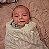 baby, infant, newborn, swaddled, smiling, face, portrait, bed, bedspread, blanket, pink, indoors, sleeping, lying_down, child, cute, head, eyes, clothing, cozy