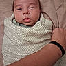 newborn, baby, infant, sleepy, swaddled, blanket, portrait, face, eyes, nose, mouth, indoor, close_up, adult_hand, adult_arm, wristband, textile, cozy, lying_down, family