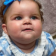 Evangeline is registered to the contest to win money with this photo: baby, child, face, headband, blue_bow, curly_hair, clothing, dress, frilly_collar, portrait, closeup, cute, infant, skin, cheeks, eyes, person, smile, texture, background