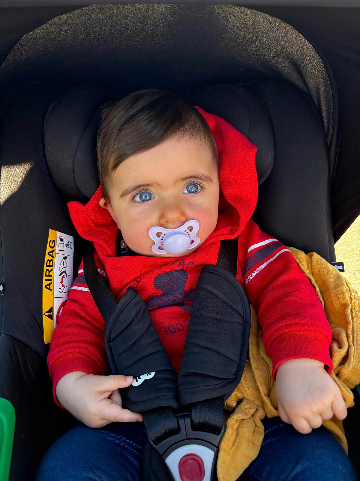 Esmée participe au concours pour gagner de l'argent avec cette photo : baby, car_seat, pacifier, red_hoodie, blue_eyes, child, blanket, straps, safety_belt, infant, cute, portrait, young_child, indoors, clothing, hand, seat, child_safety, baby_fashion, casual