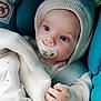 baby, infant, pacifier, blanket, hat, clothing, hand, face, eyes, car_seat, child, cute, cozy, warm, indoors, portrait, newborn, soft_texture, comfort, sleepy
