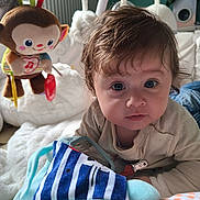 Iris participe au concours pour gagner de l'argent avec cette photo : baby, blanket, child, closeup, clothing, colorful, curious, cute, face, happy, home, indoors, infant, lying_down, monkey_toy, person, playtime, plush_toy, soft_toys, young_child