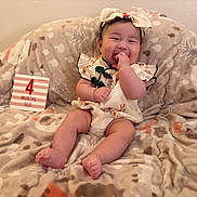 Bailey joined the competition — help win amazing prizes! adorable, baby, blanket, child, clothing, comfortable, cozy, cute, fingers, happy, headband, indoors, infant, patterned, portrait, relaxed, sitting, smiling, soft, young