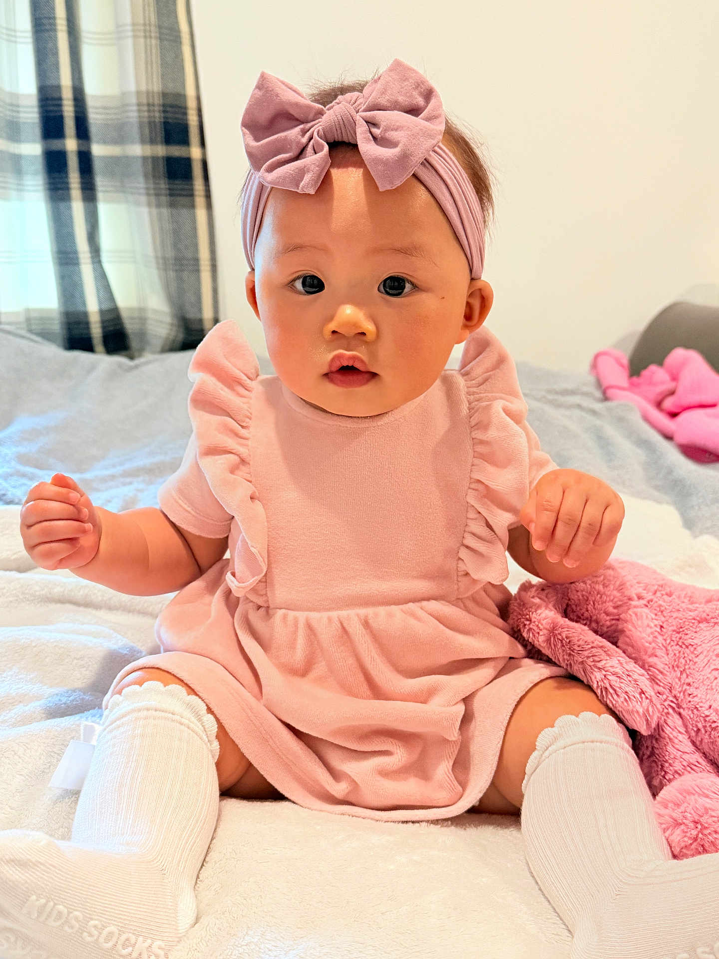 Orianna joined the competition — help win amazing prizes! baby, child, pink_dress, headband, bow, socks, blanket, bed, indoors, curtains, plush, sitting, cute, portrait, soft_lighting, infant, clothing, room, person, comfortable