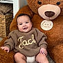 baby, child, teddy_bear, plush_toy, carpet, sweater, knitwear, smile, indoor, cozy, soft, cute, infant, person, hand, foot, furniture, blanket, room, happy