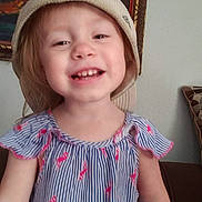 Audrie joined the competition — help win amazing prizes! beige_hat, child, couch, cute, dress, face, frame, happy, hat, headwear, indoor, painting, person, pillow, pink_flamingos, portrait, smiling, striped_dress, toddler, young_child