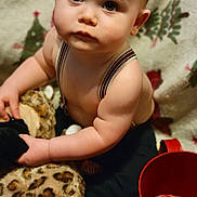 Micheal is registered to the contest to win money with this photo: baby, child, face, eyes, expression, suspenders, plush_toy, leopard_print, blanket, indoor, red_cup, curious, closeup, skin, hand, infant, portrait, person, young_child, cute