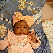 Yasmin participe au concours pour gagner de l'argent avec cette photo : baby, infant, child, pink_clothing, headband, bow, floral_pattern, cushion, blanket, hand, face, portrait, cute, indoors, soft_lighting, young_child, smile, person, resting, closeup