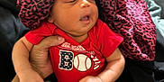 Orion joined the competition — help win amazing prizes! baby, child, infant, onesie, red_clothing, hand, bed, blanket, socks, indoor, person, face, leopard_print, bonnet, family, curious, candid, holding, soft_fabric, casual