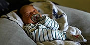Orion joined the competition — help win amazing prizes! baby, sleeping, pacifier, blanket, striped_clothing, couch, indoor, soft_light, cozy, infant, resting, comfort, child, home, furniture, portrait, relaxation, peaceful, wrapped, young