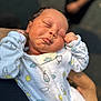 newborn, baby, sleeping, onesie, infant, hands, face, peaceful, patterned_clothing, person, closeup, soft_focus, cradled, outdoor, arm, cute, skin, expression, tiny, resting