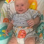 Archie is registered to the contest to win money with this photo: baby, child, smiling, infant, baby_seat, colorful, animal_print, clothing, cute, indoors, happy, person, seat, toddler, pattern, soft_focus, face, legs, hand, comfort