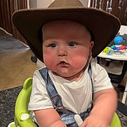 Ryder joined the competition — help win amazing prizes! baby, child, cowboy_hat, baby_seat, indoor, curtains, toy, table, face, blue_eyes, chubby_cheeks, white_tshirt, denim_overalls, hand, home_interior, framed_photo, curious_expression, furniture, young_child, seat