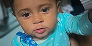 Dream is registered to the contest to win money with this photo: toddler, child, baby, curly_hair, blue_onesie, pacifier_clip, hand, face, eyes, indoor, person, closeup, soft_lighting, expression, holding, reaching, brush, background_blur, skin, cute