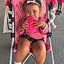 toddler, child, stroller, cookie, pink, headband, smiling, happy, snack, toy, plush, clothing, socks, shoes, outdoor, person, seatbelt, curly_hair, food, playful