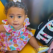 Dream joined the competition — help win amazing prizes! toddler, child, baby, curly_hair, bow, floral_dress, gold_shoes, yellow_seat, bag, paint_splatter, toy, cute, portrait, indoor, colorful, smiling, face, eyes, hand, foot