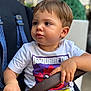 background_blur, casual_wear, child, clothing, curious, expression, face, grip, hand, indoor, person, portrait, seat, short_hair, snack, stroller, table, toddler, tshirt, young
