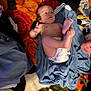Leo is registered to the contest to win money with this photo: baby, diaper, blue_cloth, colorful_carpet, floral_pattern, infant, feet, hands, denim_jacket, brush, container, fabric, person, indoor, laying_down, skin, toddler, blanket, clothing, floor