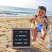 Bennett joined the competition — help win amazing prizes! baby, beach, sand, ocean, child, chair, sunglasses, sign, summer, sunny, water, waves, barefoot, smiling, outdoor, casual, relaxing, portrait, playful, vacation