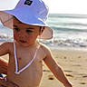 toddler, child, hat, white_hat, beach, ocean, waves, sand, sunny, outdoor, summer, striped_shorts, person, skin, hand, baby, portrait, cute, sun_protection, vacation