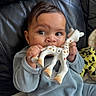 baby, blue_clothing, child, closeup, cute, expression, face, giraffe, hands, home, indoor, infant, leather_couch, playing, plush_toy, remote_control, sitting, soft_toy, teething_toy, young_child