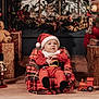 baby, santa_hat, plaid, christmas, holiday, teddy_bear, gift, toy_train, nutcracker, window, snow, festive, decorations, wood_floor, red_clothing, child, smiling, indoor, cozy, holiday_season